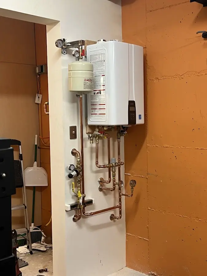 Plumbing technician inspecting water heater connections in Unadilla